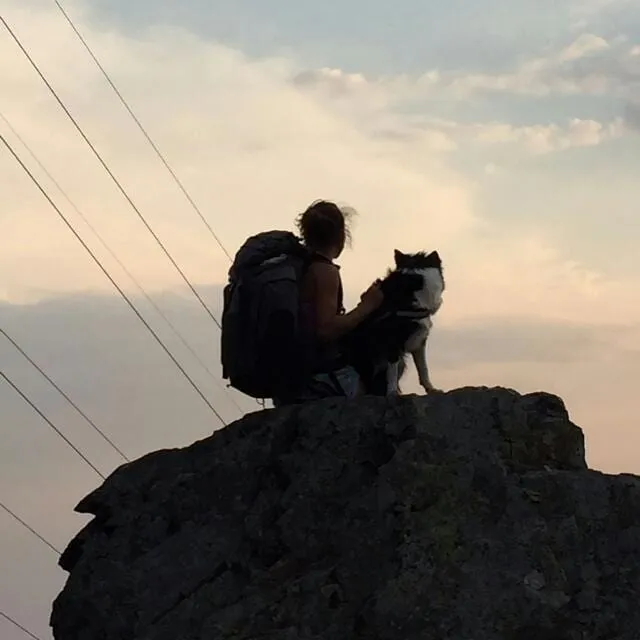Controluce su uno sperone di roccia, con lo zaino e il cane